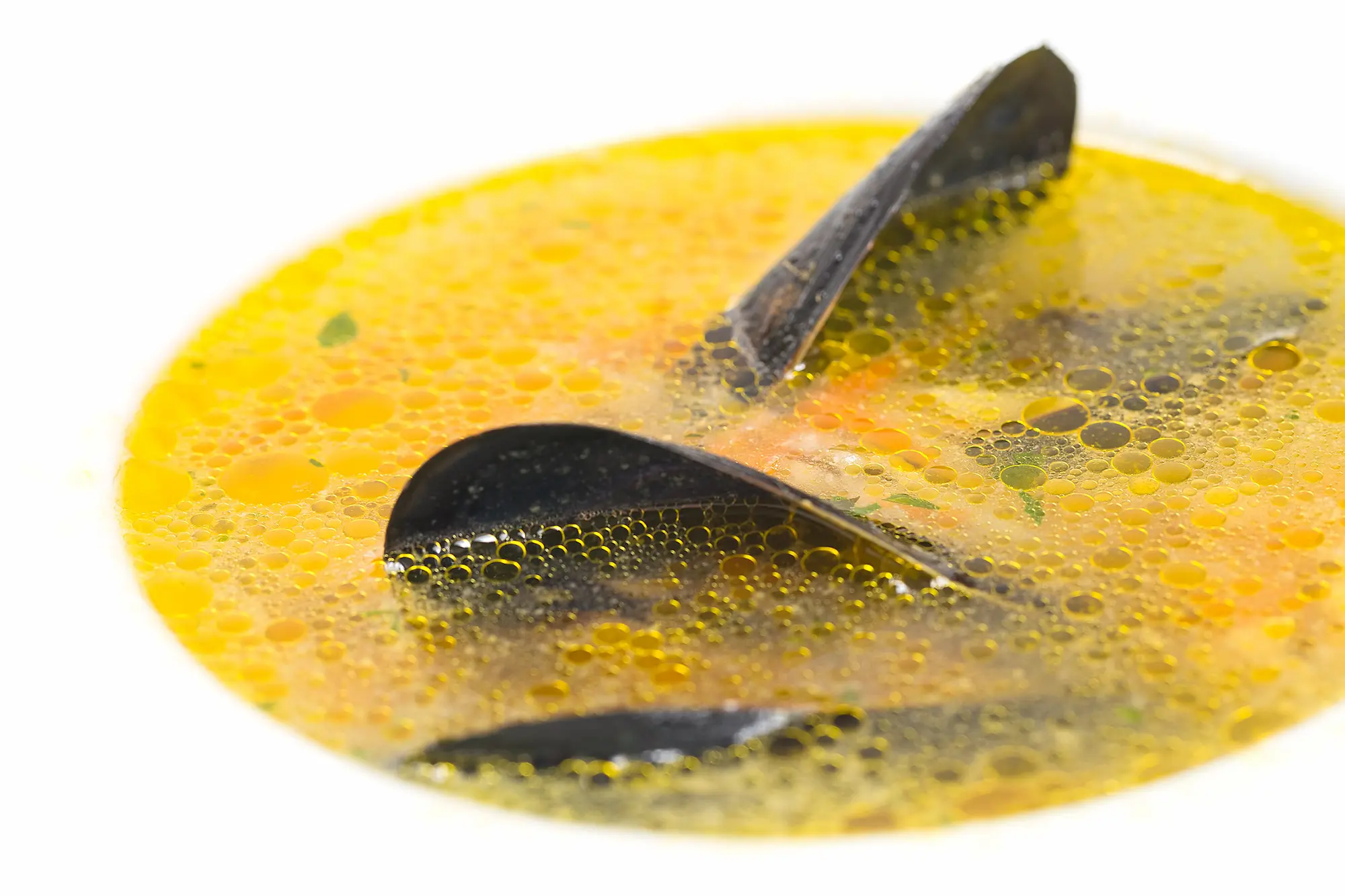 Fish soup with mussels, olive-oil droplets, macro close-up.